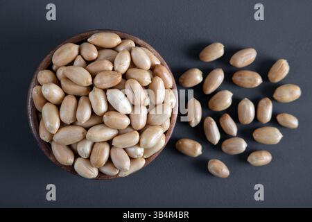 Bowl full of roasted peeled peanuts on dark background,top view Stock Photo
