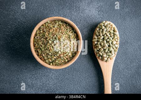 A bowl filled with a pile of natural dried thyme, alongside a spoon containing thyme seeds Stock Photo