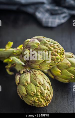 Ripe artichokes plant on a black table. Stock Photo