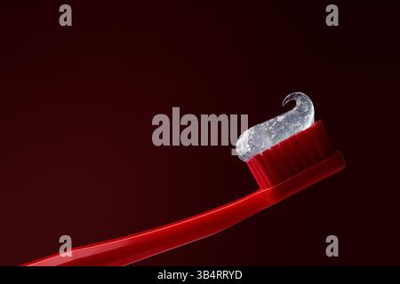 Red plastic toothbrush with transparent toothpaste on a dark red background. Dentistry. Stock Photo
