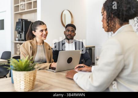 Business partners discussing with consultant using laptop during meeting in modern office Stock Photo