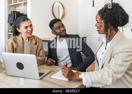Business professionals collaborating on project, engaging in productive discussion, using laptop and taking notes Stock Photo