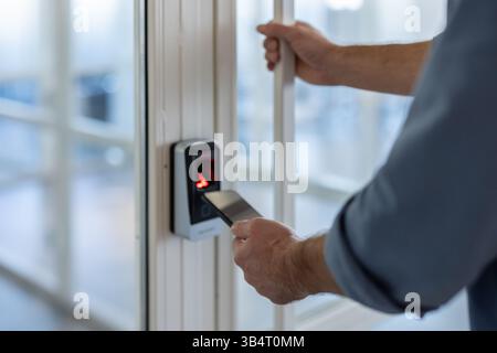 A person is using their smartphone to access an office door using a security system. Stock Photo