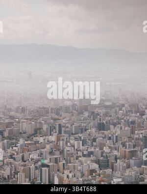 Aerial view of Osaka cityscape during a stormy dramatic sunset showing highways towers and dense residential districts Stock Photo