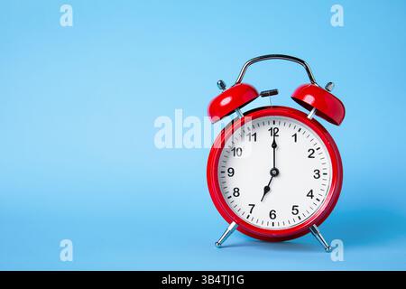 Classic Red Alarm Clock on Light Blue Background Stock Photo