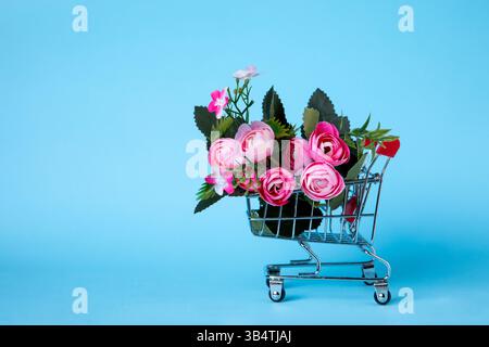 Mini Shopping Cart Filled With Pink Roses on Blue Background Stock Photo
