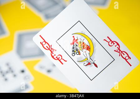 Joker card among other cards on a yellow background. Stock Photo