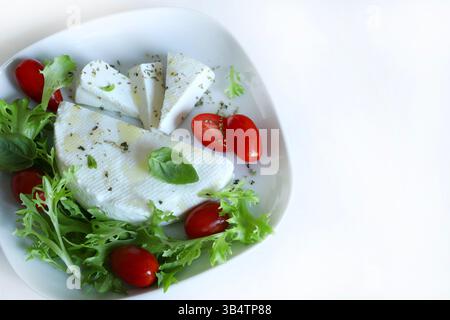 "Primosale", typical sicilian pecorino cheese. Fresh cheese with vegetables and basil leaf, olive oil on a white plate white background. Stock Photo