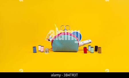 Yellow background. Banner on the theme of needlework. Items needed for sewing. Scissors, threads, bag, needles, and a centimeter tape. Sewing kit. Stock Photo