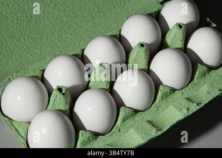 Cardboard green egg box on a gray background, a lot of eggs are in the box. Stock Photo