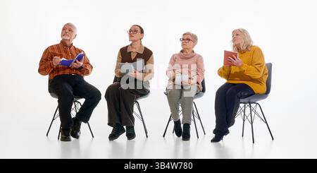 Senior group sitting with notebooks and listening attentively. Seminar, adult education, interest, active participation. Stock Photo