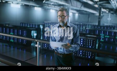 Big Data Center with Server Racks: Professional Specialist Using Tablet Computer, Activating Servers Standing In Warehouse. Information Technology Concept. Cloud Computing, Web Service. Medium Shot. Stock Photo