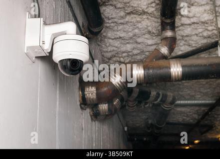Security camera in parkade of building. Wall mounted dome camera with motion sensor. Wide screen high definition surveillance system. CCTV camera for Stock Photo