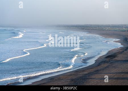 Waves from the Pacific Ocea break on the deserted beach at sunrise in
