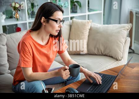 Woman using laptop and drinking coffee Stock Photo