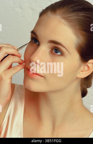 Studio portrait of young woman professional model applying makeup. Stock Photo