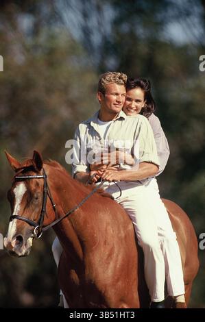 Close up of young couple outdoors riding together on one horse. Stock Photo