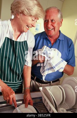 Senior couple washing dishes in the kitchen at home. Stock Photo