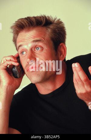 Close up of man indoors speaking on burner cell phone. Stock Photo