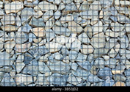 There are many different stones and cobblestones in the cage. Metal protection for rocks. Stock Photo