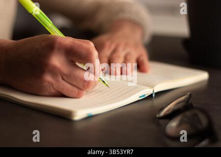 Close up image of human holding pen and writing something on blank white page in notebook Stock Photo
