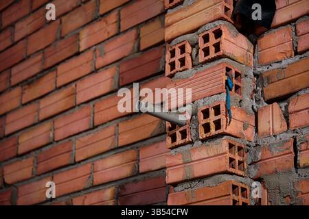 Hollow red brick wall under construction with utility pipe Stock Photo