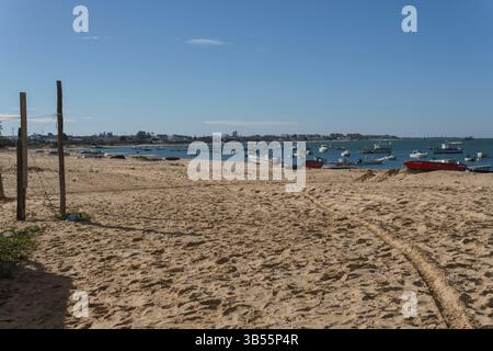 Sunny Day at Peaceful Beach with Anchored Boats in Distance Stock Photo