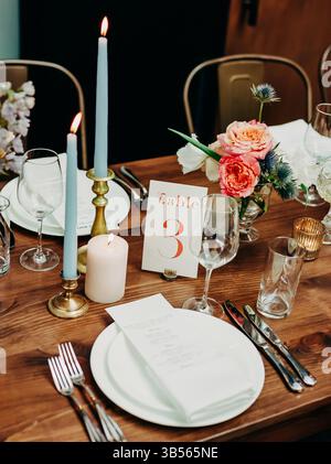 A beautifully arranged dinner table featuring flowers, candles, and elegant place settings for a special gathering. Stock Photo