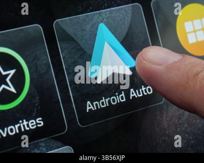 Finger touching android auto interface on vehicle touchscreen dashboard displaying digital navigation controls. Tbilisi, Georgia - March 31, 2025. Stock Photo