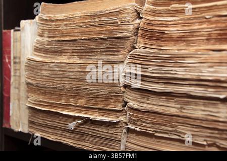 Aged paper documents stacked in rows on a shelf, photographed in close-up, with a focus on texture and history preservation Stock Photo