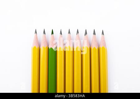 Individuality, uniqueness, different. Green pencil among yellow ones on white background, top view Stock Photo