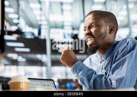 General manager sits at his computer frustrated and overwhelmed by the workload of business tasks. Entrepreneur dealing with fatigue after experiencing pressure at the workplace. Stock Photo