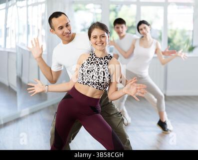 Cheerful young couple practicing playful Charleston in dance studio Stock Photo