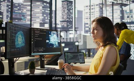 System administrator at work doing debugging of AI software using PC, checking glitches in lines of code. IT specialist in office fixing artificial intelligence coding issues using computer, camera B Stock Photo