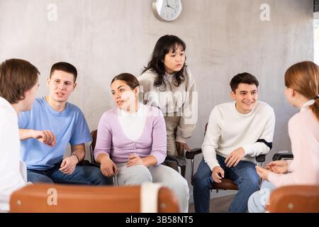 Group of students sitting in circle studying together in study hall of university Stock Photo