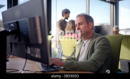 Businessman thinking and working on laptop in office with colleagues Stock Photo