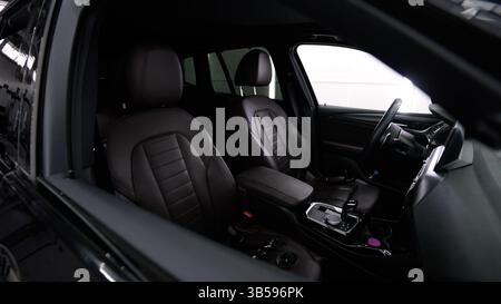 Luxurious black leather seats and steering wheel are highlighted in the interior of a modern vehicle Stock Photo