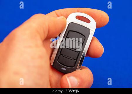 four-button remote control for opening garage doors held in hand on blue background Stock Photo