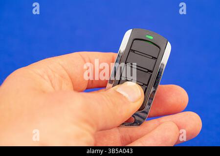 four-button remote control for opening garage doors held in hand on blue background Stock Photo