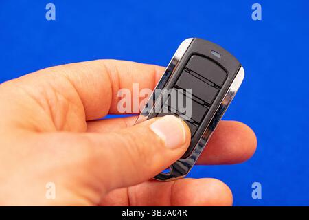 four-button remote control for opening garage doors held in hand on blue background Stock Photo