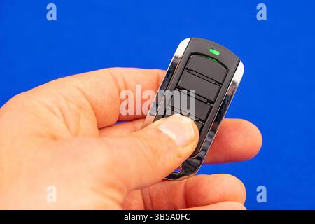 four-button remote control for opening garage doors held in hand on blue background Stock Photo