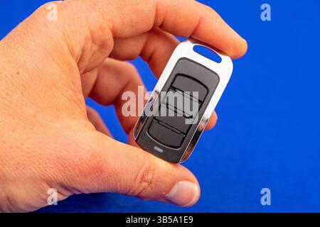 four-button remote control for opening garage doors held in hand on blue background Stock Photo