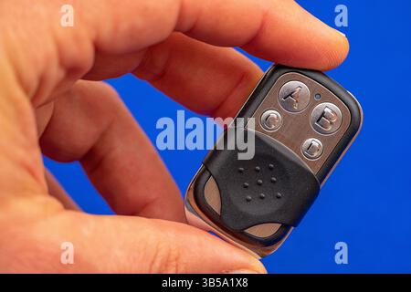 four-button remote control for opening garage doors held in hand on blue background Stock Photo