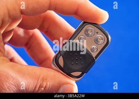 four-button remote control for opening garage doors held in hand on blue background Stock Photo