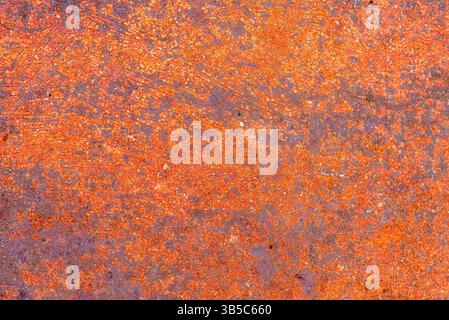 Close-up of an abstract rust texture in vivid orange and purple tones, showing natural surface oxidation and gritty industrial decay. Stock Photo