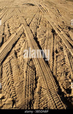 Sandy surface with tyre tracks crisscrossing in various directions Stock Photo