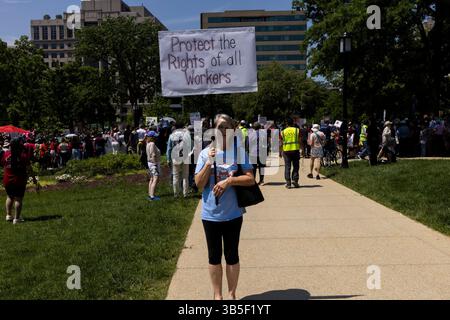 A demonstrator holds a sign while protesters gather in Washington, DC, to participate in a march commemorating workers' rights on May 1, 2025. They protest against U.S. President Donald Trump and his administration and address key issues like immigration, education, and healthcare. Hundreds of similar rallies are taking place across the country as part of a larger national movement. Stock Photo