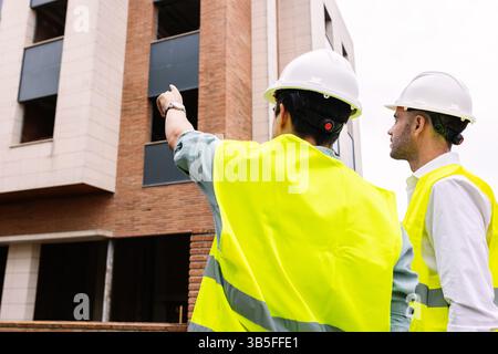 Engineers discussing building project at construction site Stock Photo