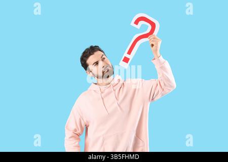 Thoughtful man with question mark on blue background Stock Photo