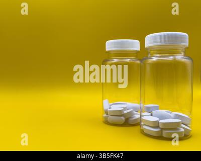 White tablets in two transparent jars on yellow background, front view, against virus and cold Stock Photo